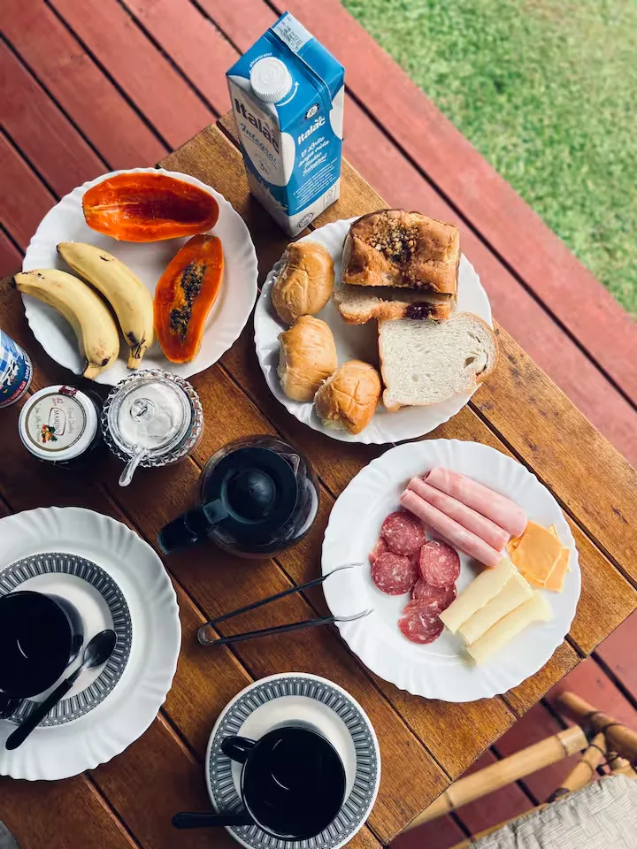 Mesa de café da manhã do Encosta da Serra, com pão, frutas, queijo, presunto e café coado